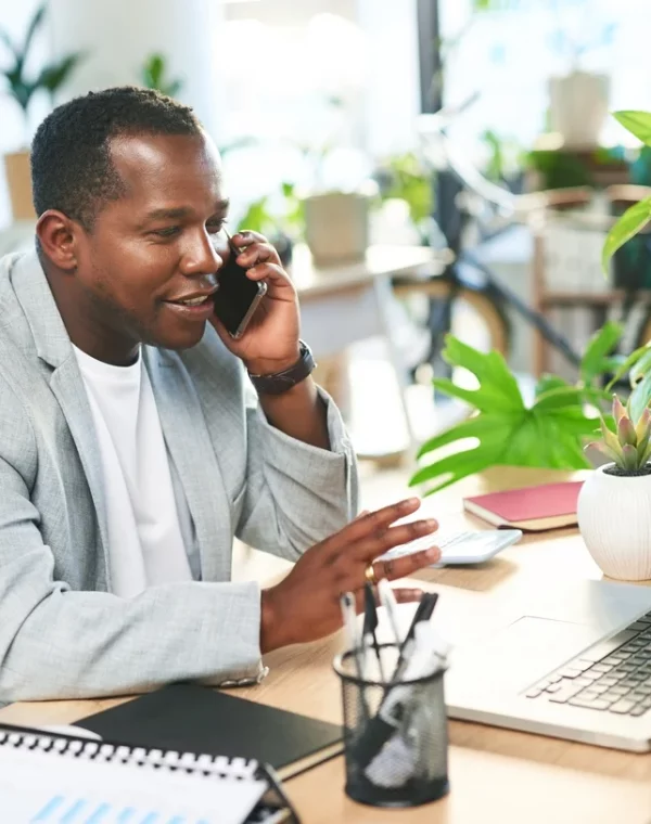 phone-call-business-and-happy-black-man-at-laptop-in-office-company-or-digital-management-manager-mobile-talking-and-computer-technology-for-networking-consulting-and-smartphone-communication